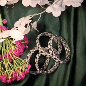 Emerald floral diamond cut bangles on dark green fabric